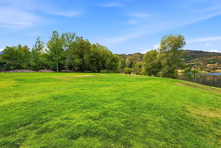 Expansive grassy lawn with established trees and a tranquil body of water