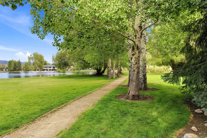 Expansive green lawn with mature trees and a walking path