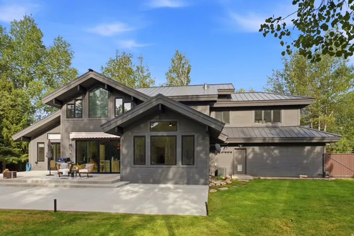 Contemporary exterior with multiple rooflines, a metal roof, an expansive concrete patio, and mature trees