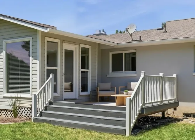 Exterior deck with composite steps, white railing, and multiple windows