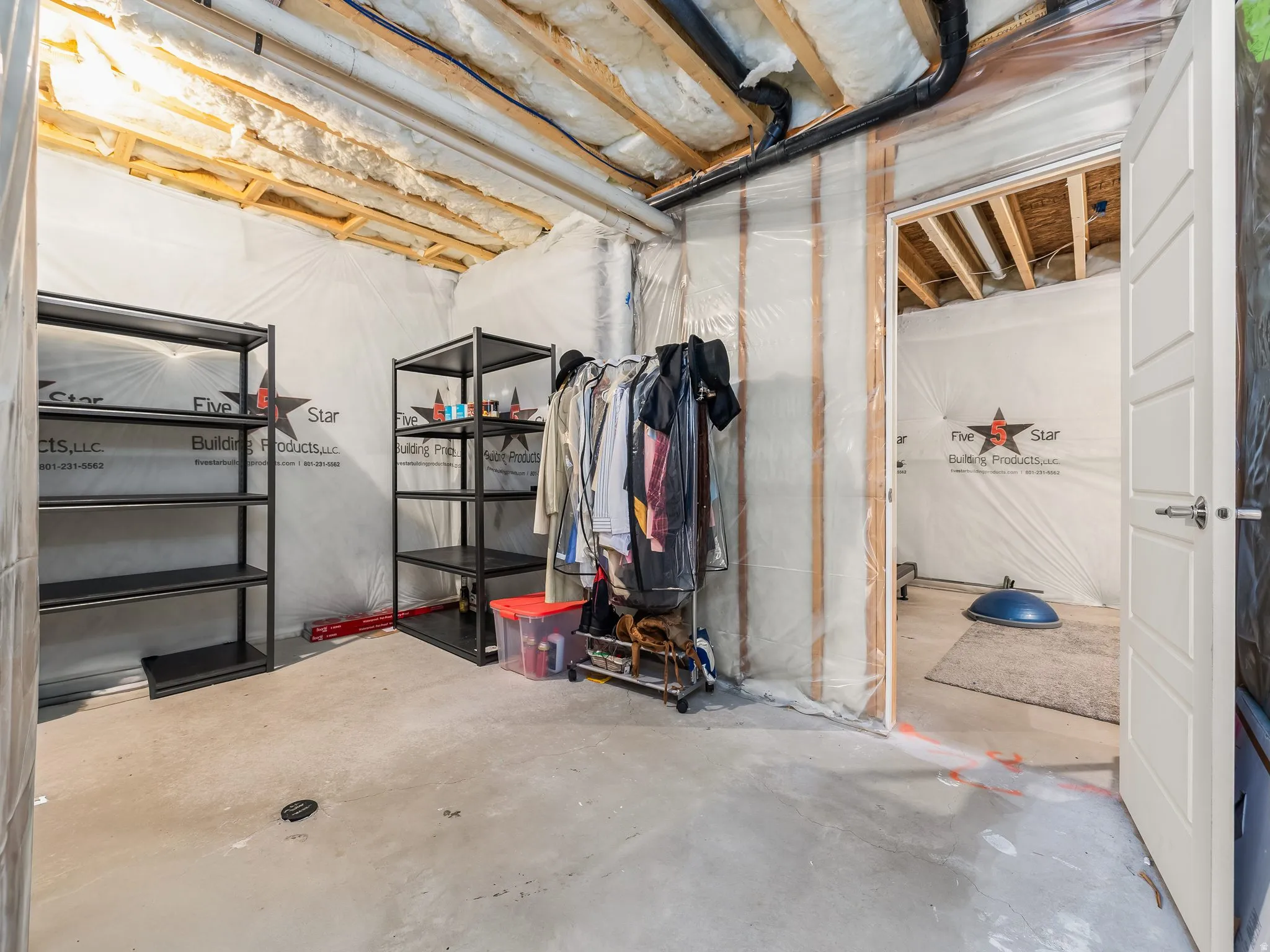 Unfinished basement space featuring exposed joists, concrete flooring, and an open doorway