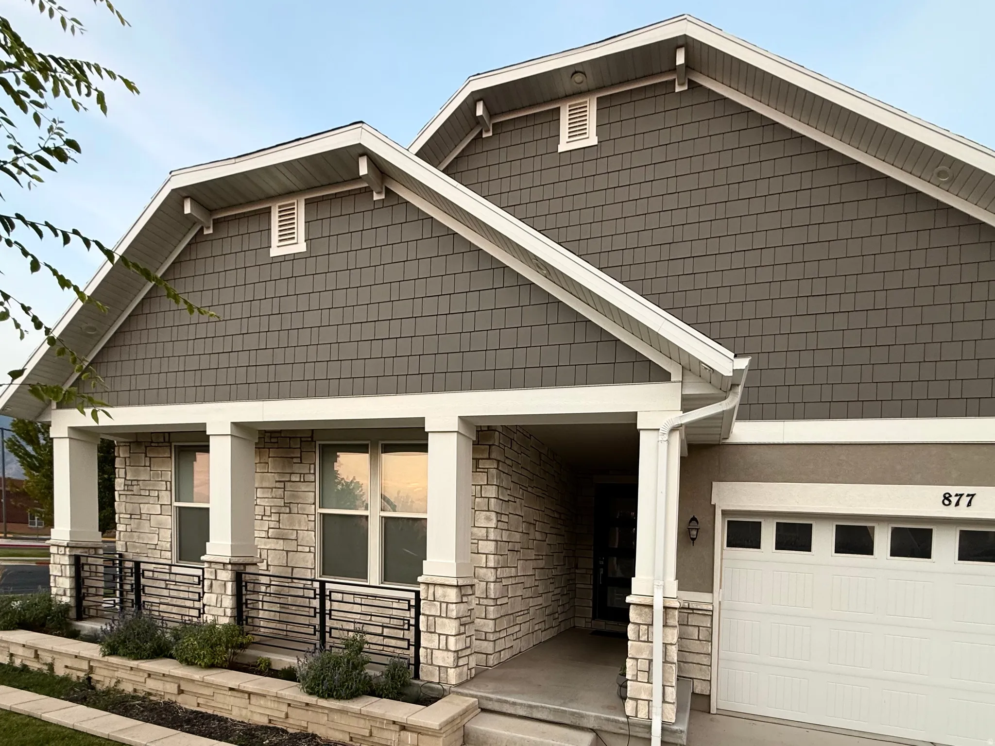 Craftsman-style exterior featuring gray shake siding, light-colored stone veneer accents, and a covered porch with white columns