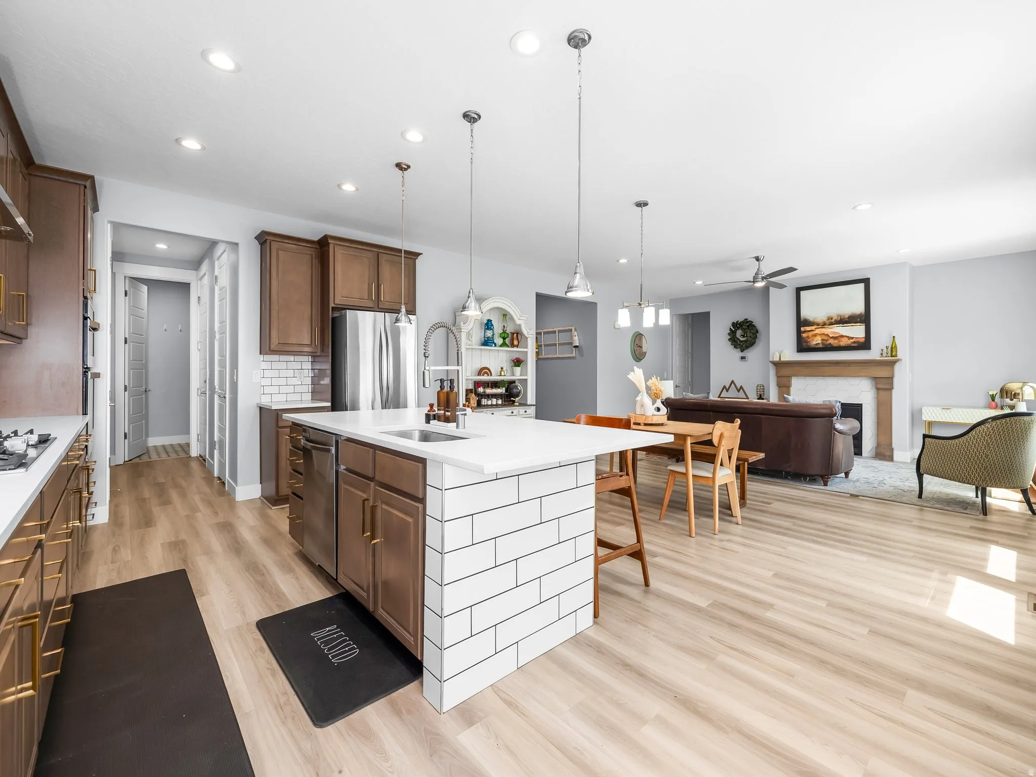 Open-concept kitchen and living area featuring wood-finish flooring, recessed lighting, and a kitchen island with white subway tile