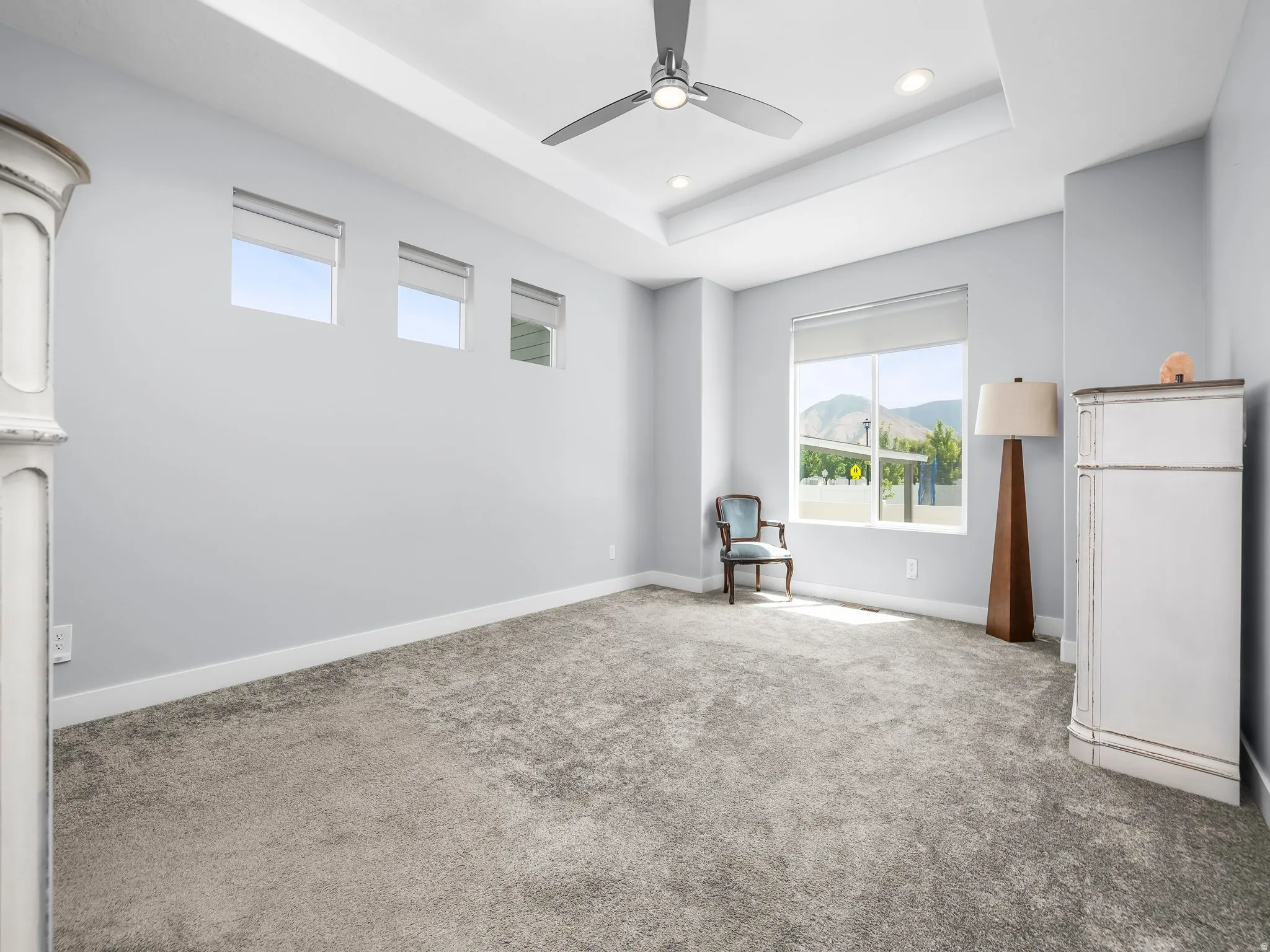 Spacious interior room featuring a tray ceiling with recessed lighting and a ceiling fan