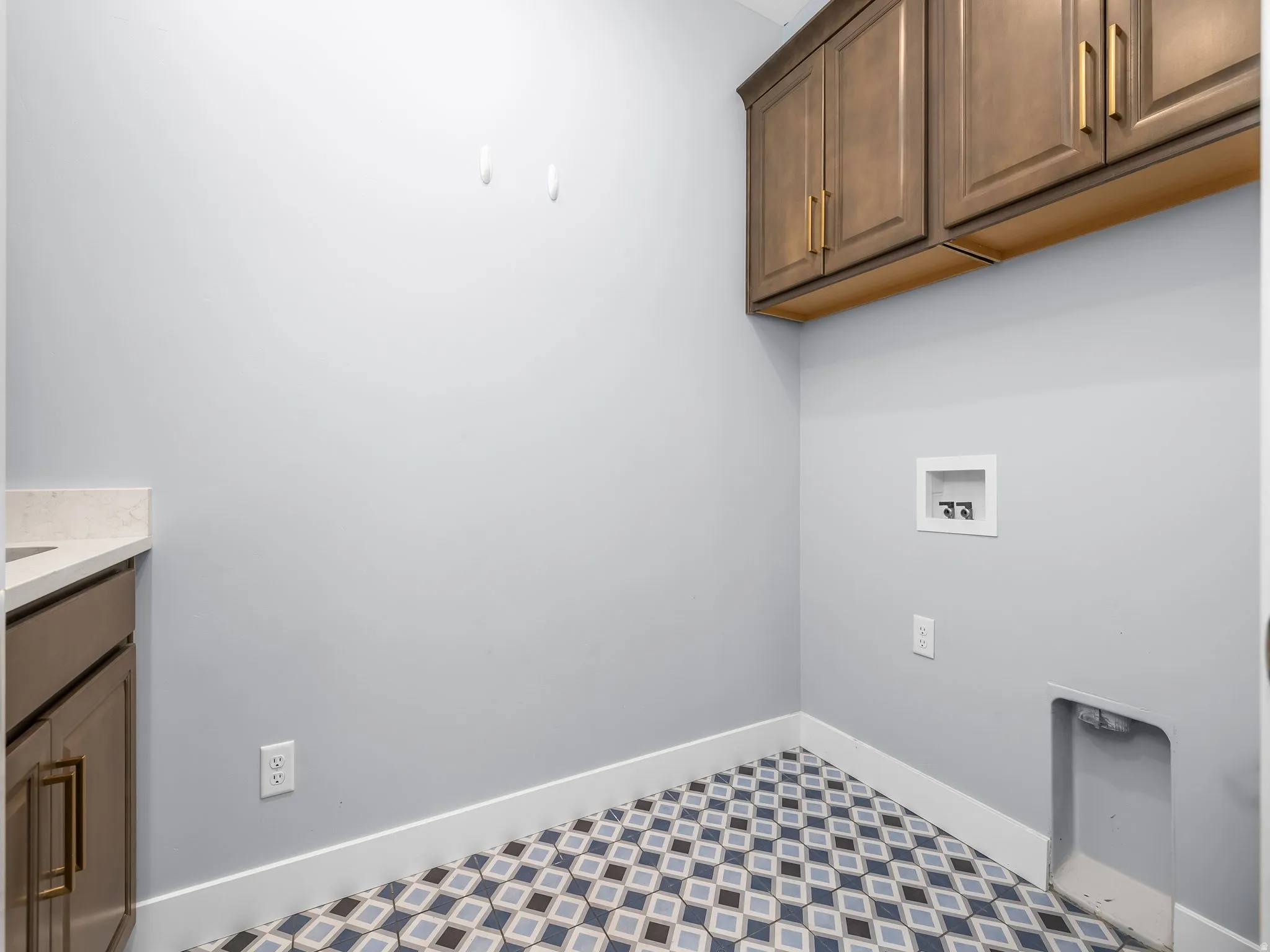 Laundry area featuring patterned tile flooring and light gray walls