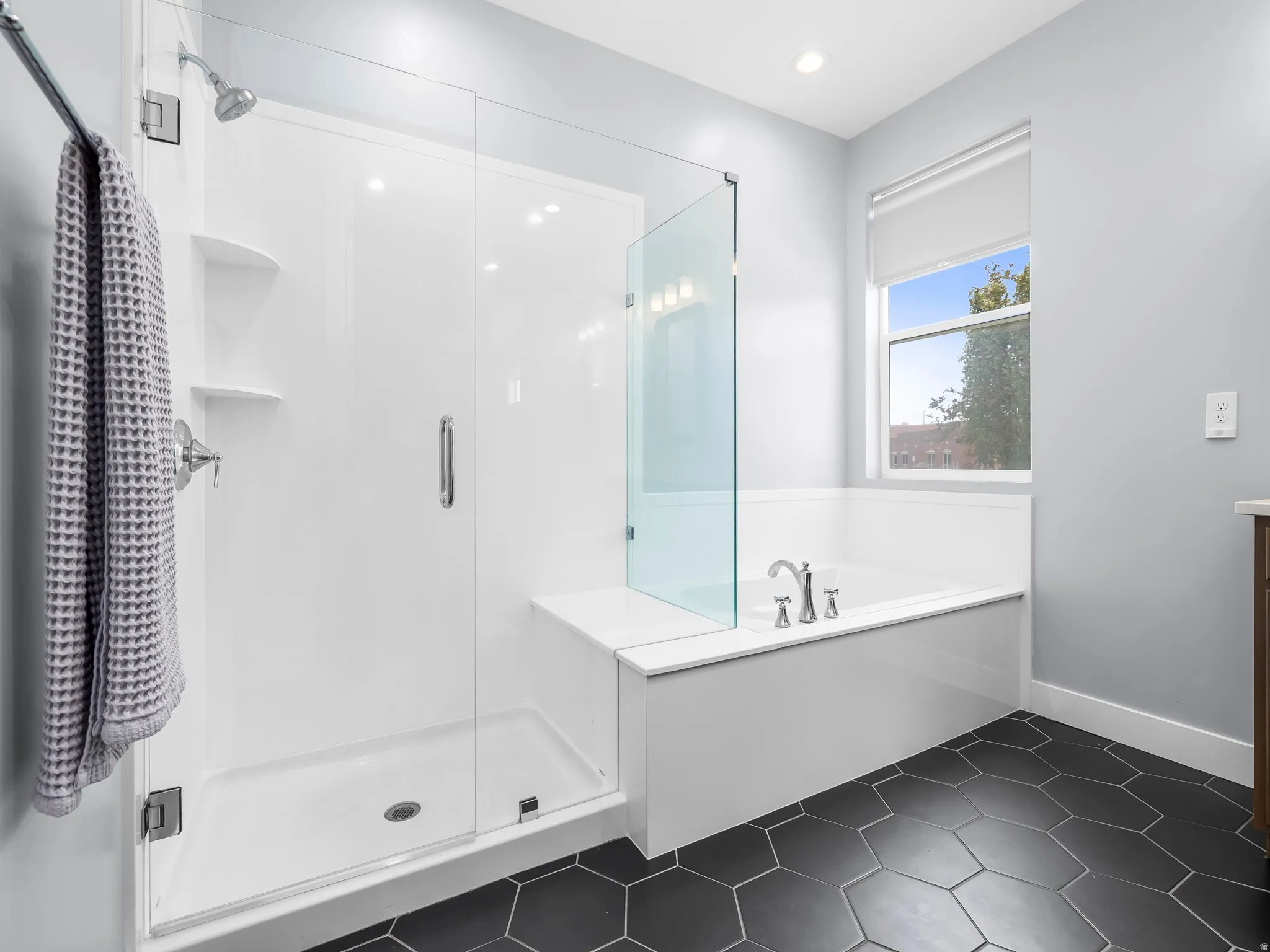 Bathroom featuring a walk-in shower with glass enclosure, separate soaking tub, and dark hexagon tile flooring