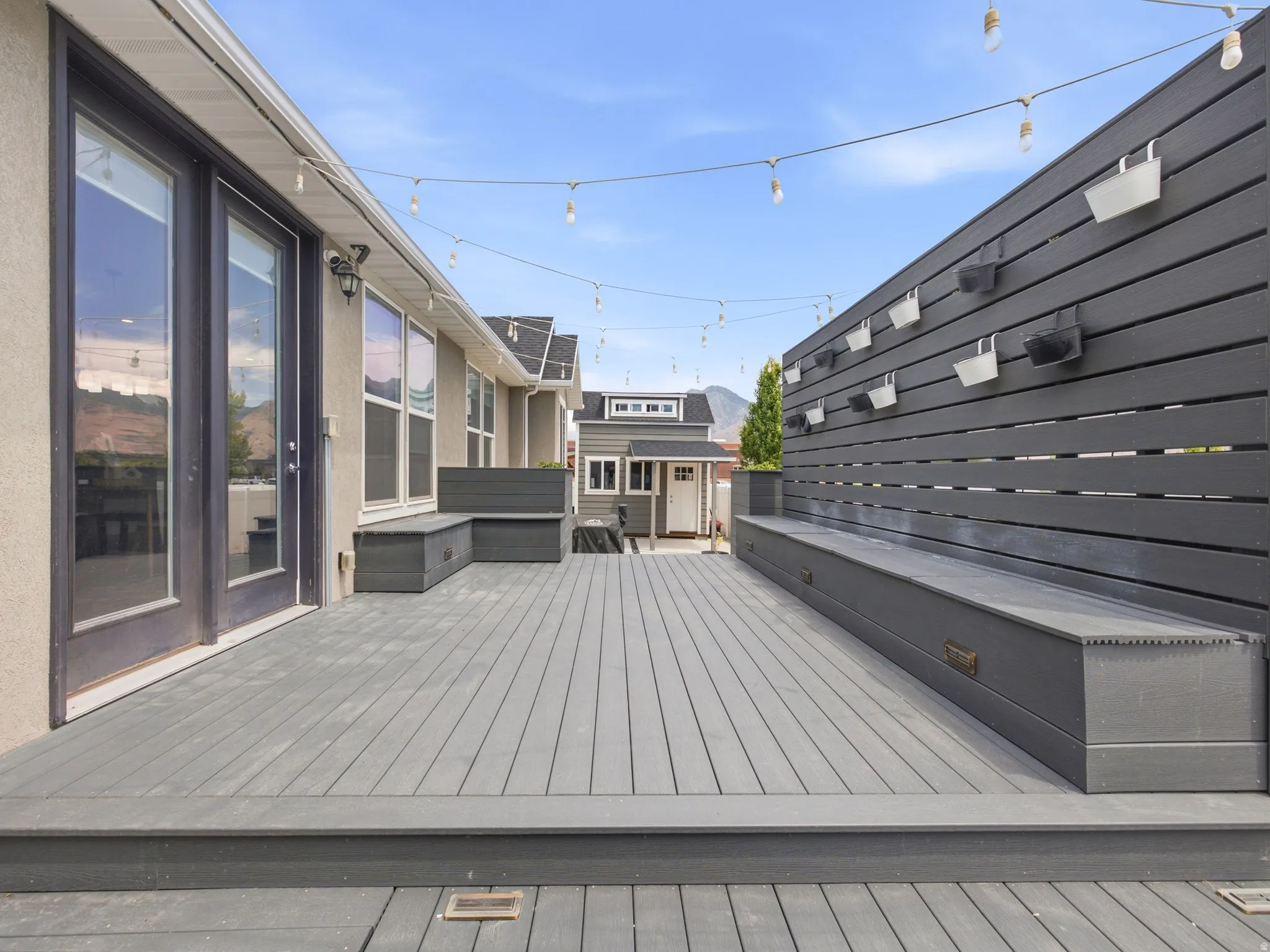 Spacious outdoor deck featuring composite decking, built-in bench seating, a privacy wall, and French patio doors