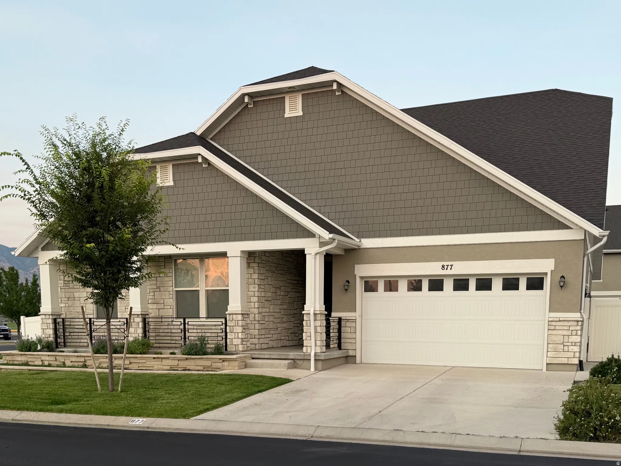 Contemporary residence featuring a gray shingle facade, white trim, and a dark shingle roof
