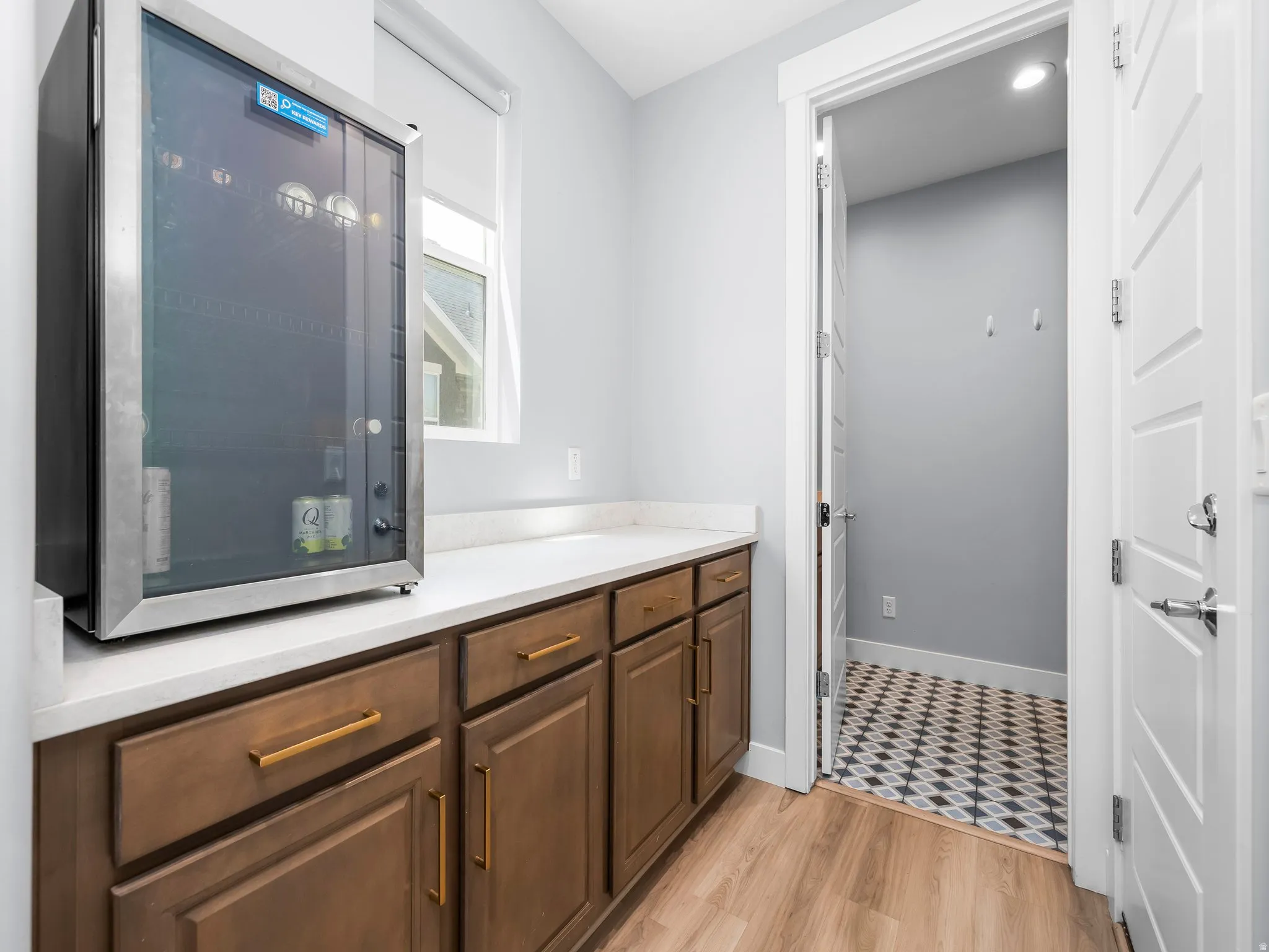 Beverage cooler integrated into the countertop space, featuring wood-finish cabinetry with gold-tone hardware
