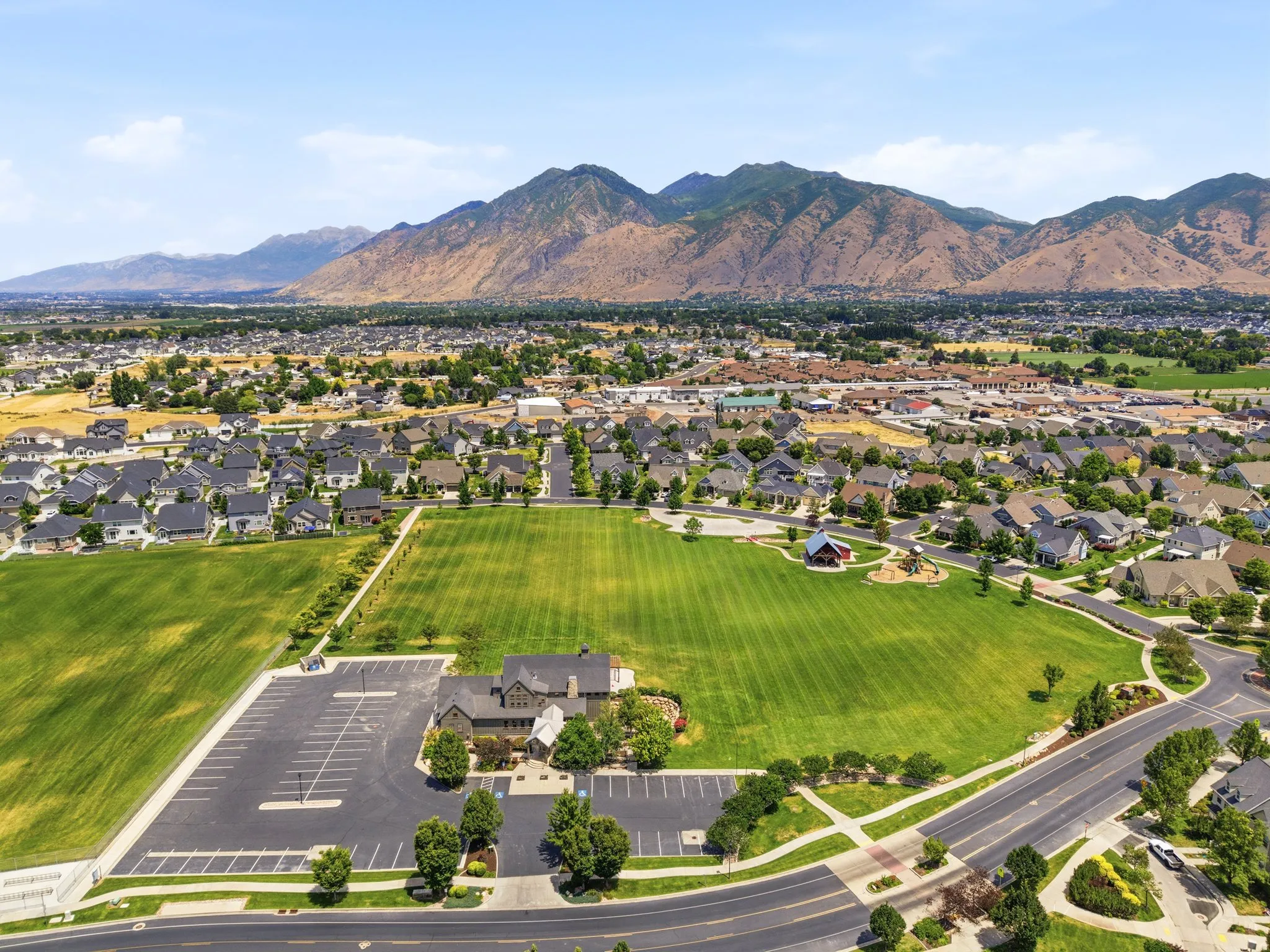 Aerial perspective showcasing a residential community with expansive green spaces and mountainous backdrops