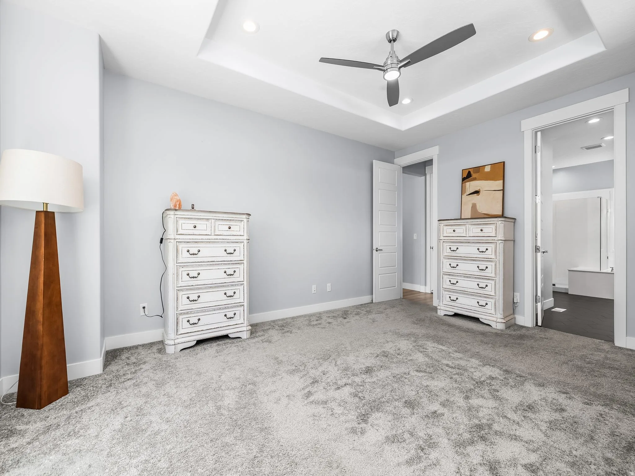 Bedroom featuring light gray carpeting, tray ceiling with recessed lighting, and a contemporary ceiling fan