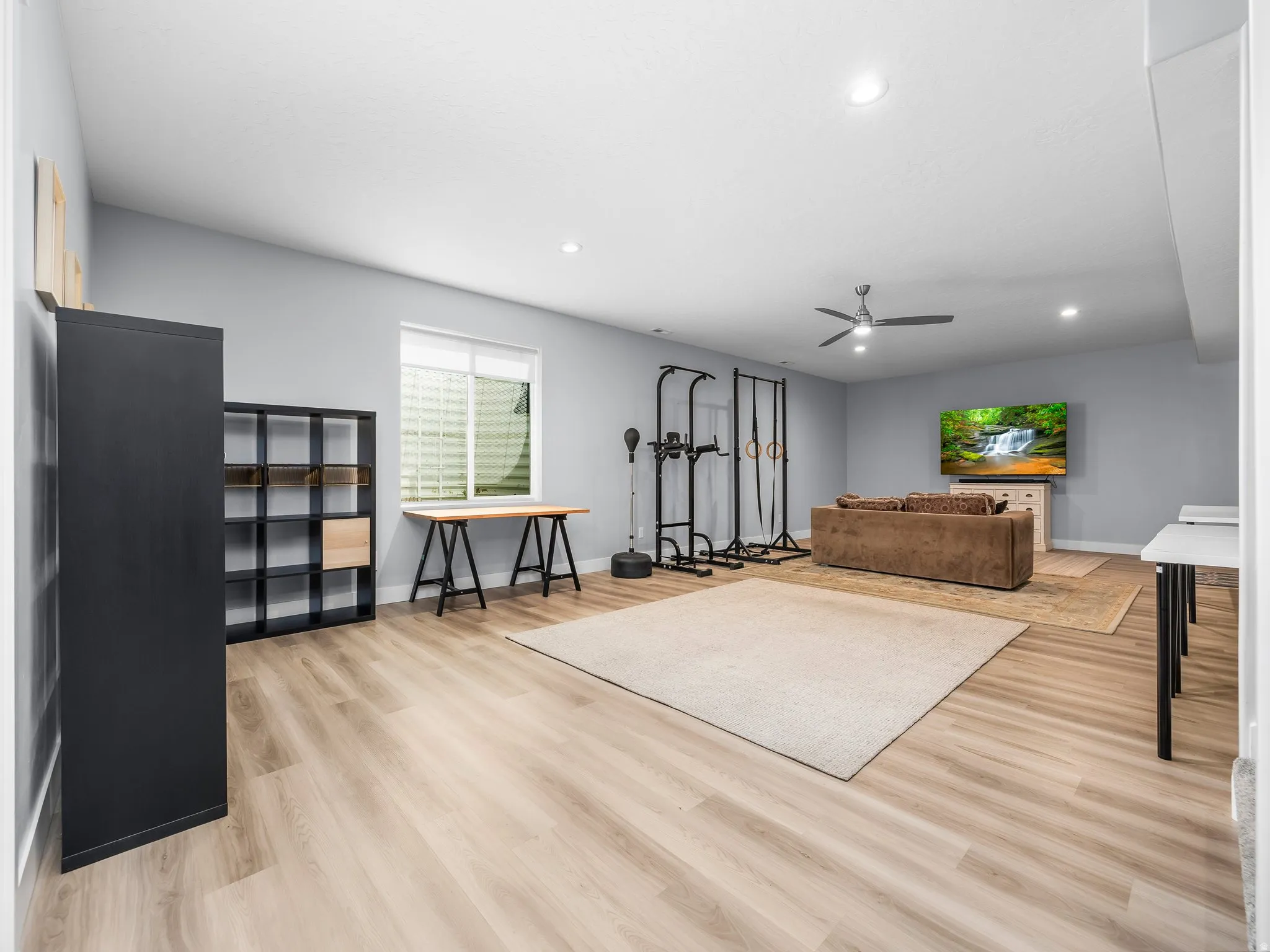 Spacious multi-purpose room featuring light wood-finish flooring, recessed lighting, and a ceiling fan