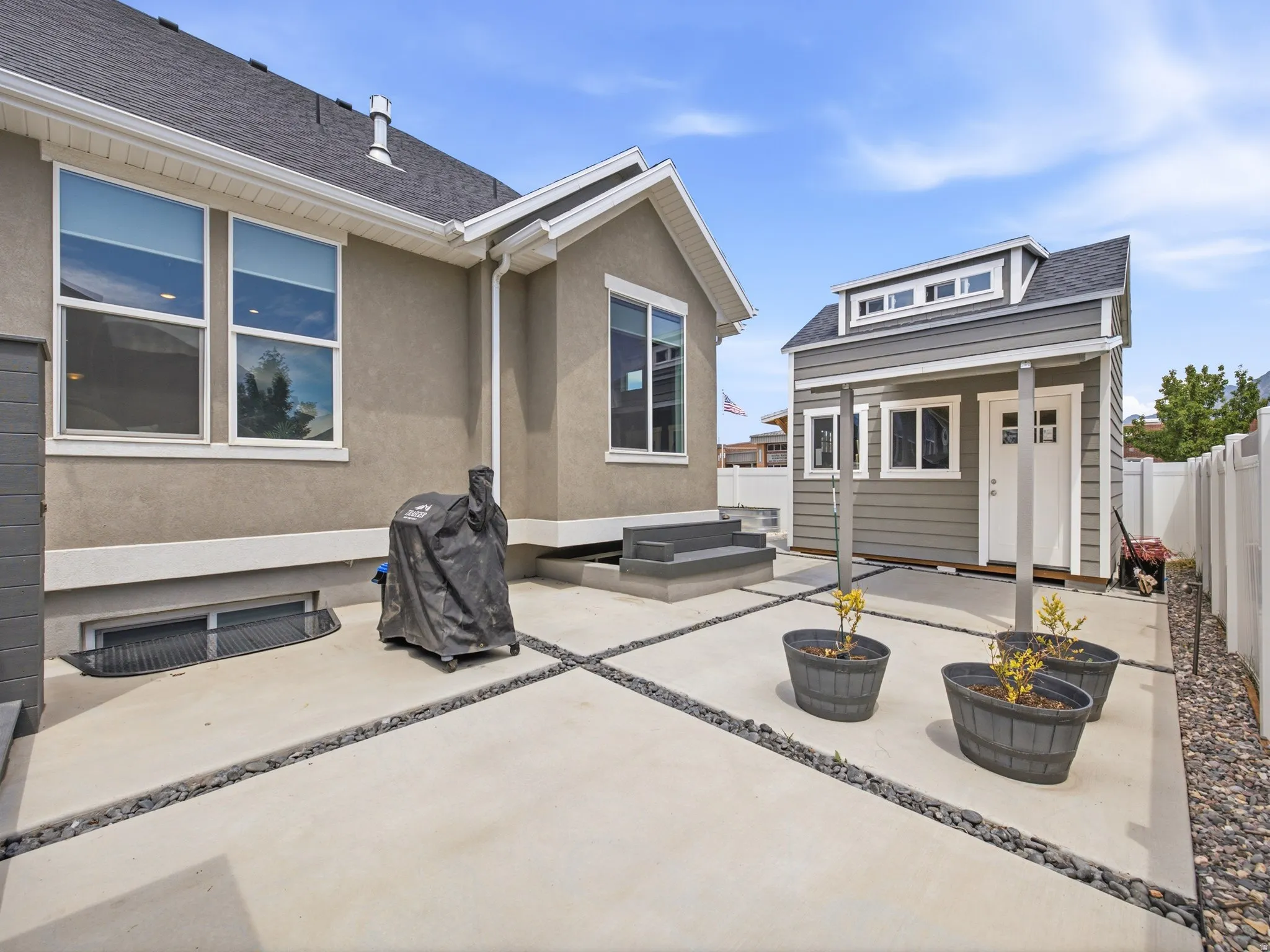 Backyard featuring a detached shed with dormer window, concrete patio with river rock accents, and a privacy fence