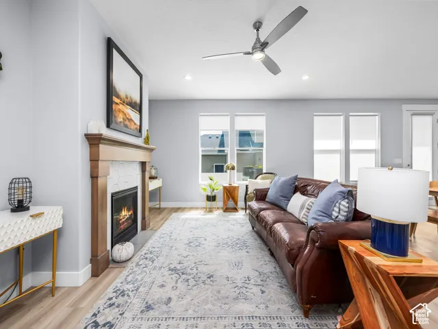 Living area featuring wood-finish flooring, a contemporary fireplace with a wood mantle and hexagonal tile surround, multiple windows, recessed lighting, and a ceiling fan