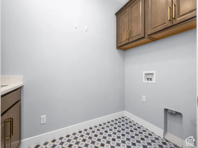 Laundry area featuring patterned tile flooring and light gray walls