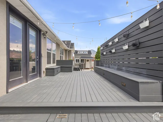 Spacious outdoor deck featuring composite decking, built-in bench seating, a privacy wall, and French patio doors