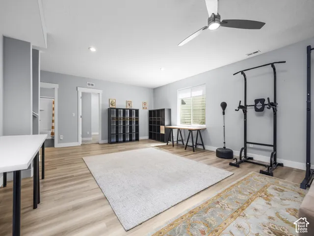 Spacious room featuring wood-finish flooring, recessed lighting, and a modern ceiling fan