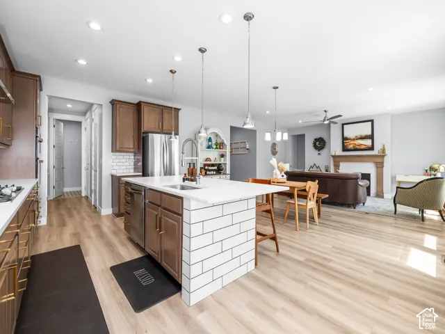 Open-concept kitchen and living area featuring wood-finish flooring, recessed lighting, and a kitchen island with white subway tile