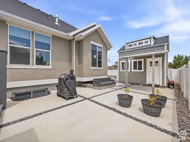 Backyard featuring a detached shed with dormer window, concrete patio with river rock accents, and a privacy fence