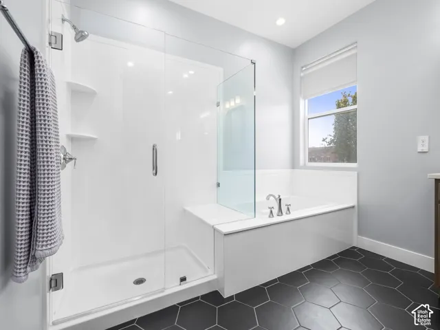 Bathroom featuring a walk-in shower with glass enclosure, separate soaking tub, and dark hexagon tile flooring