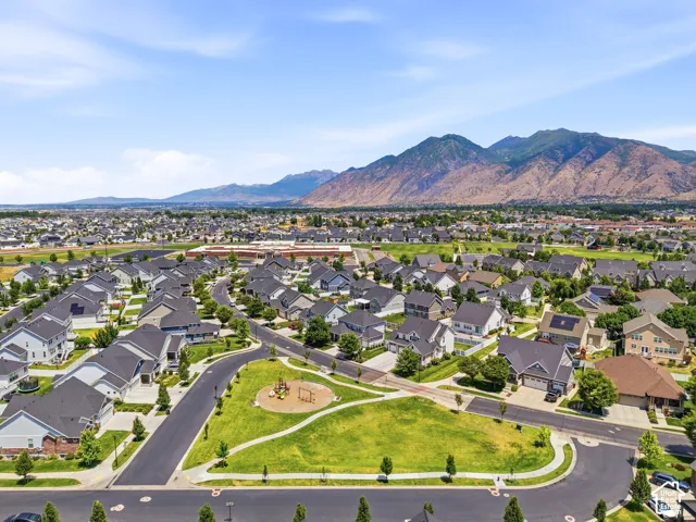 Expansive residential development featuring a community park, paved streets, and a mountainous backdrop
