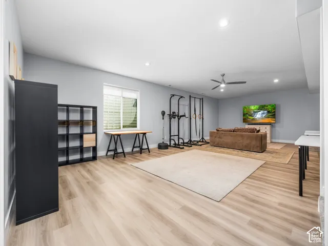 Spacious multi-purpose room featuring light wood-finish flooring, recessed lighting, and a ceiling fan