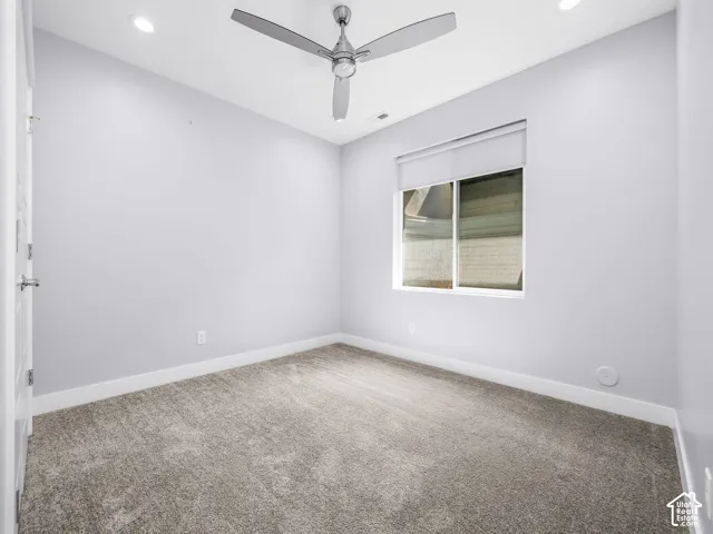Room featuring recessed lighting, a modern ceiling fan, a window with roller shade, neutral wall tones, and gray carpet flooring