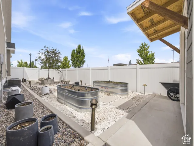 Private backyard space featuring a white vinyl fence, two galvanized planters, and a concrete patio section