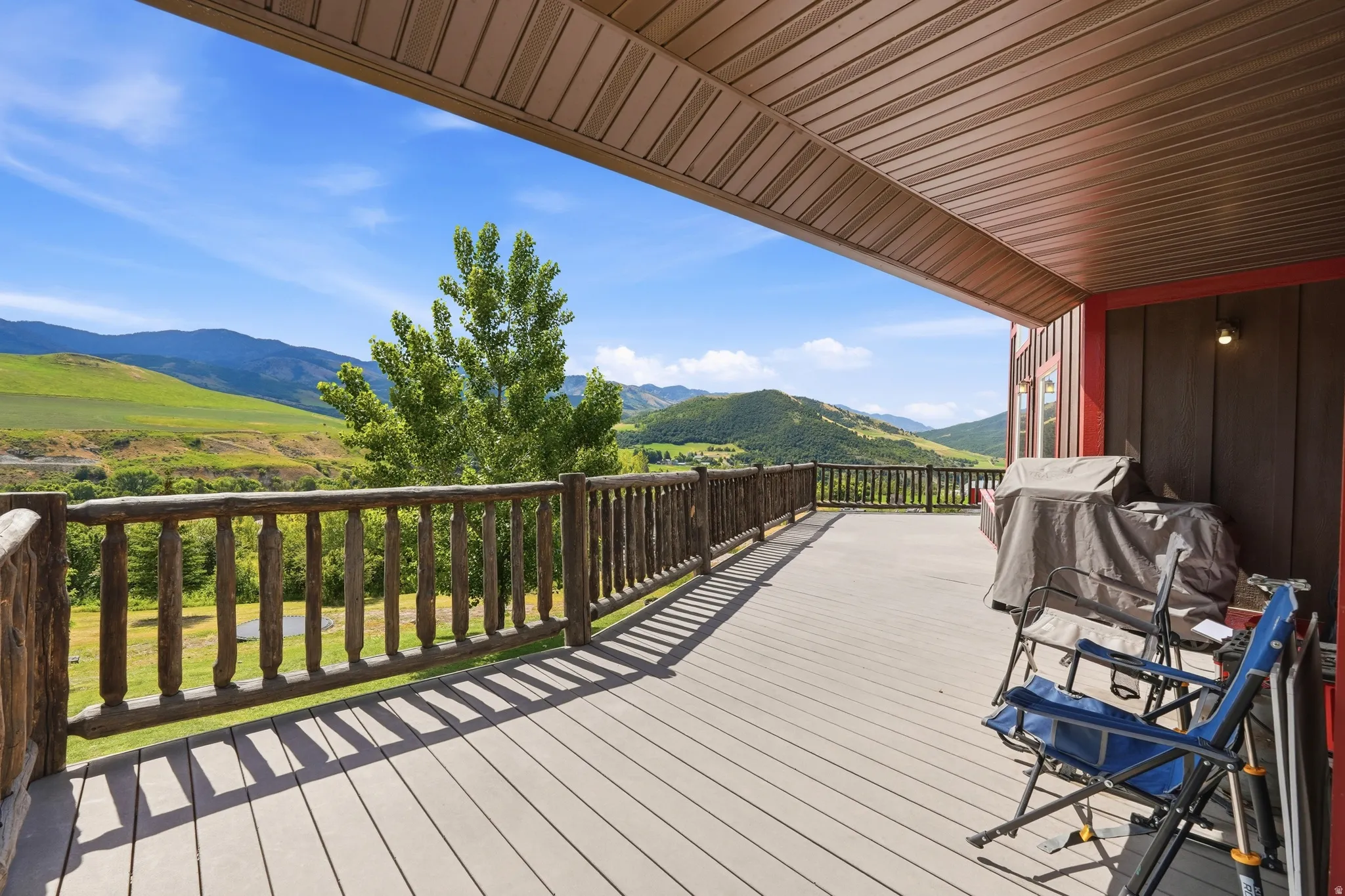Expansive covered deck featuring composite decking and a rustic wood railing
