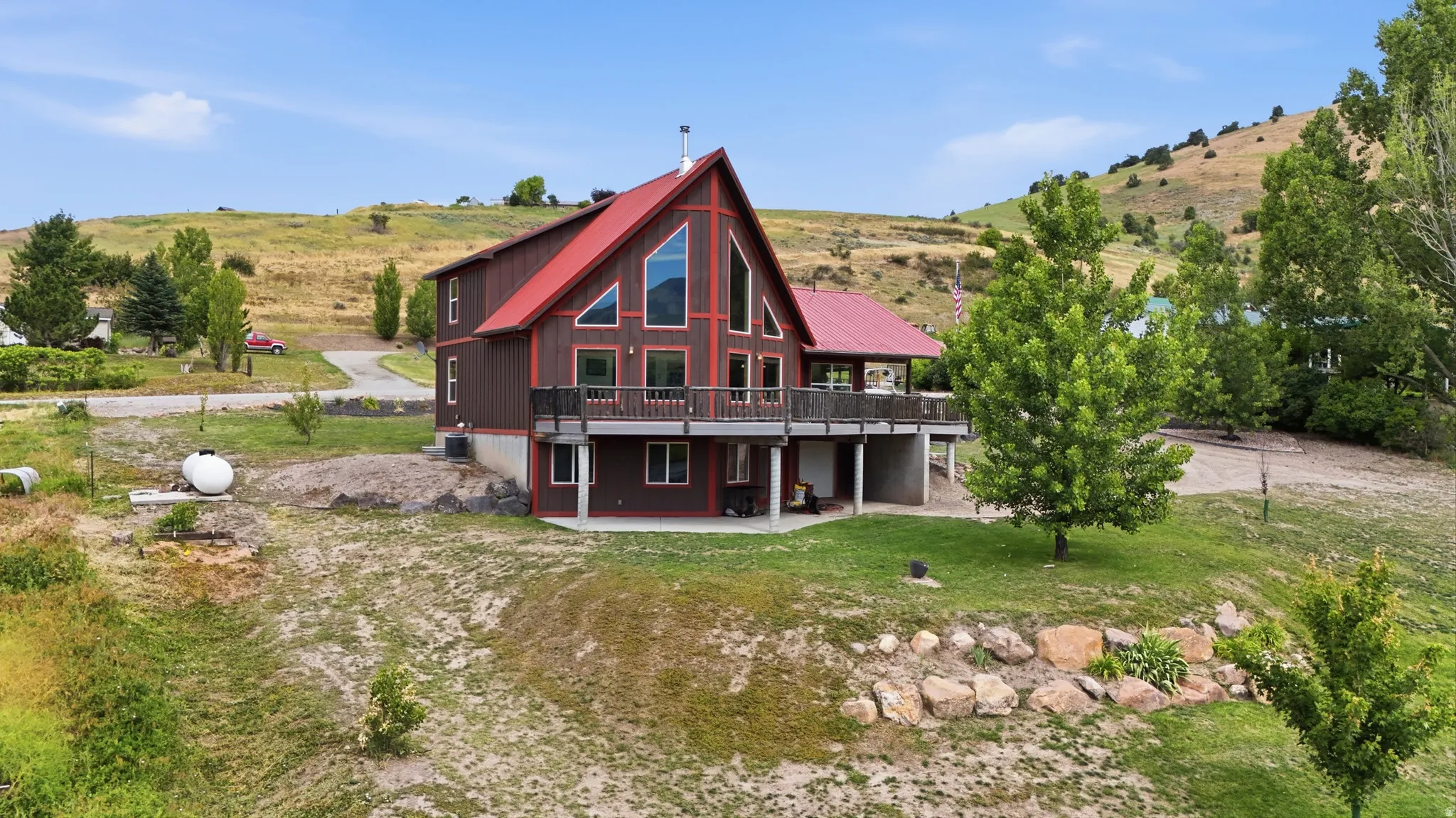 A-frame style residence featuring a prominent red metal roof, expansive upper-level balcony, and large picture windows
