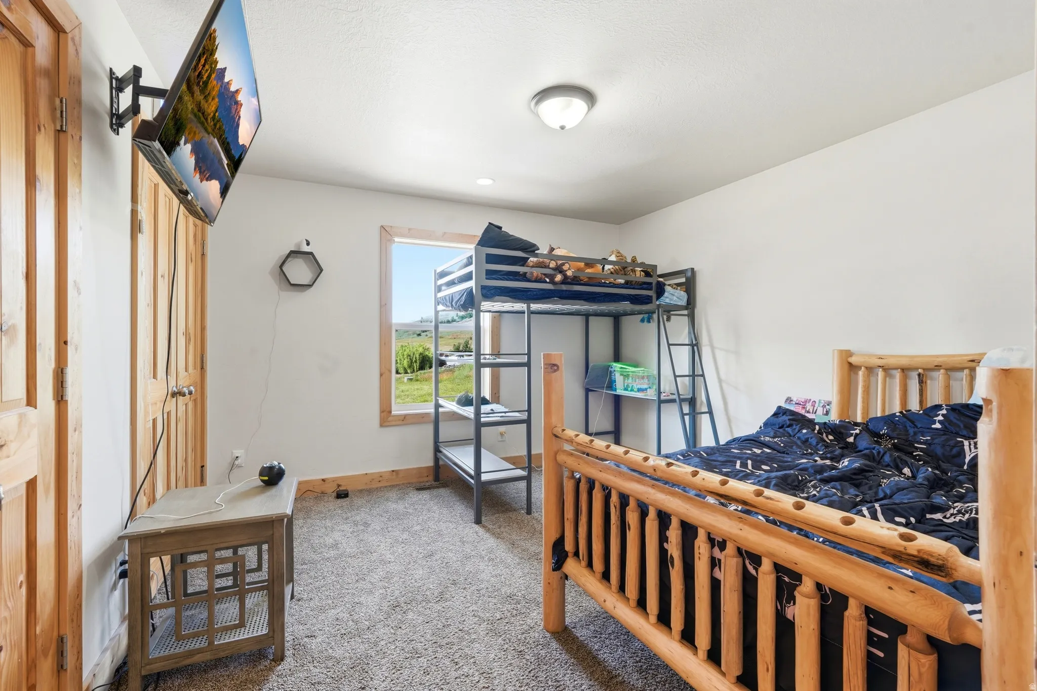 Carpeted room featuring white walls, natural wood door, and a single window with wood trim