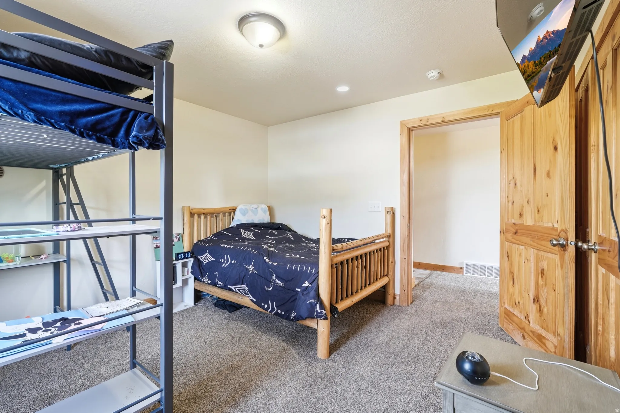 Spacious room featuring neutral-toned walls, plush carpeting, and natural wood doors with matching trim