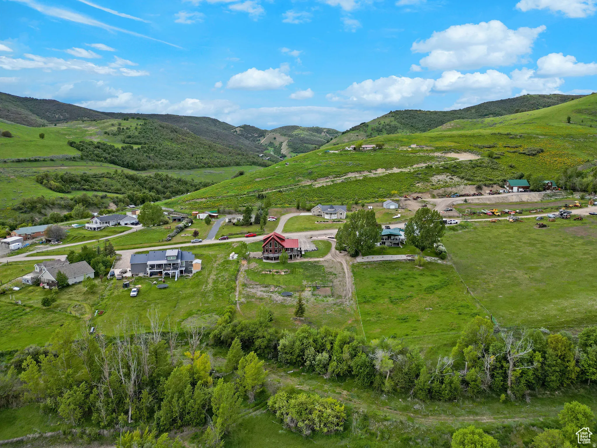 Expansive green hills surround a community of homes with paved roads