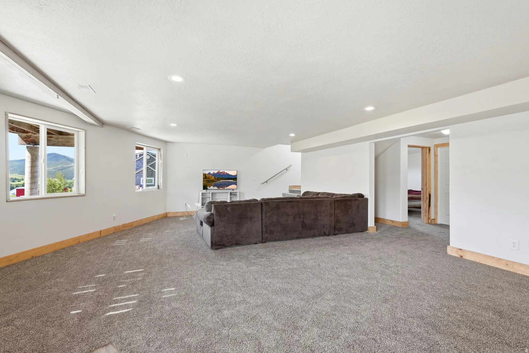 Spacious carpeted room with multiple windows, recessed lighting, and white walls