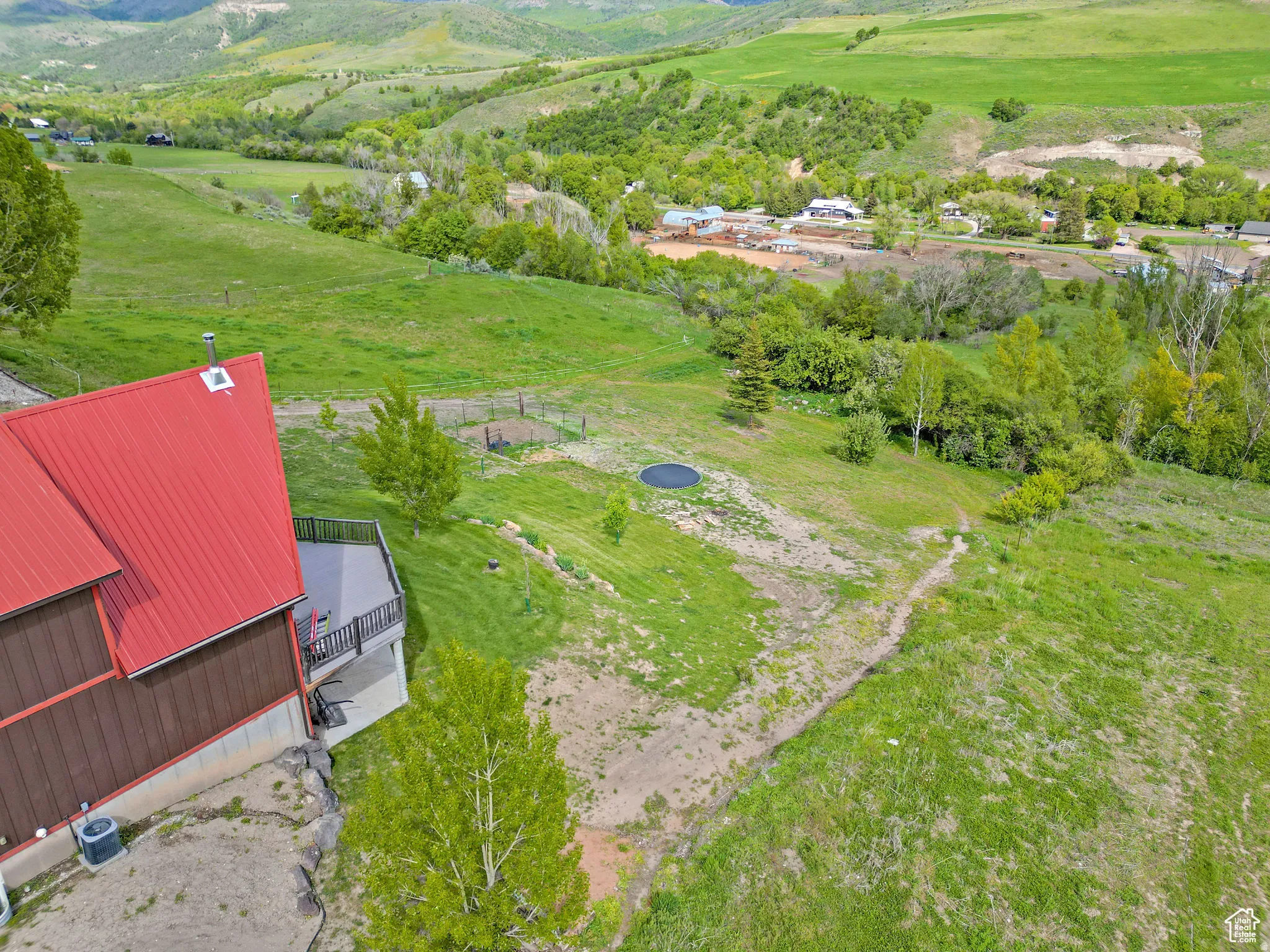 Property featuring a red metal roof, multi-level exterior deck, and a sloping, expansive grassy yard