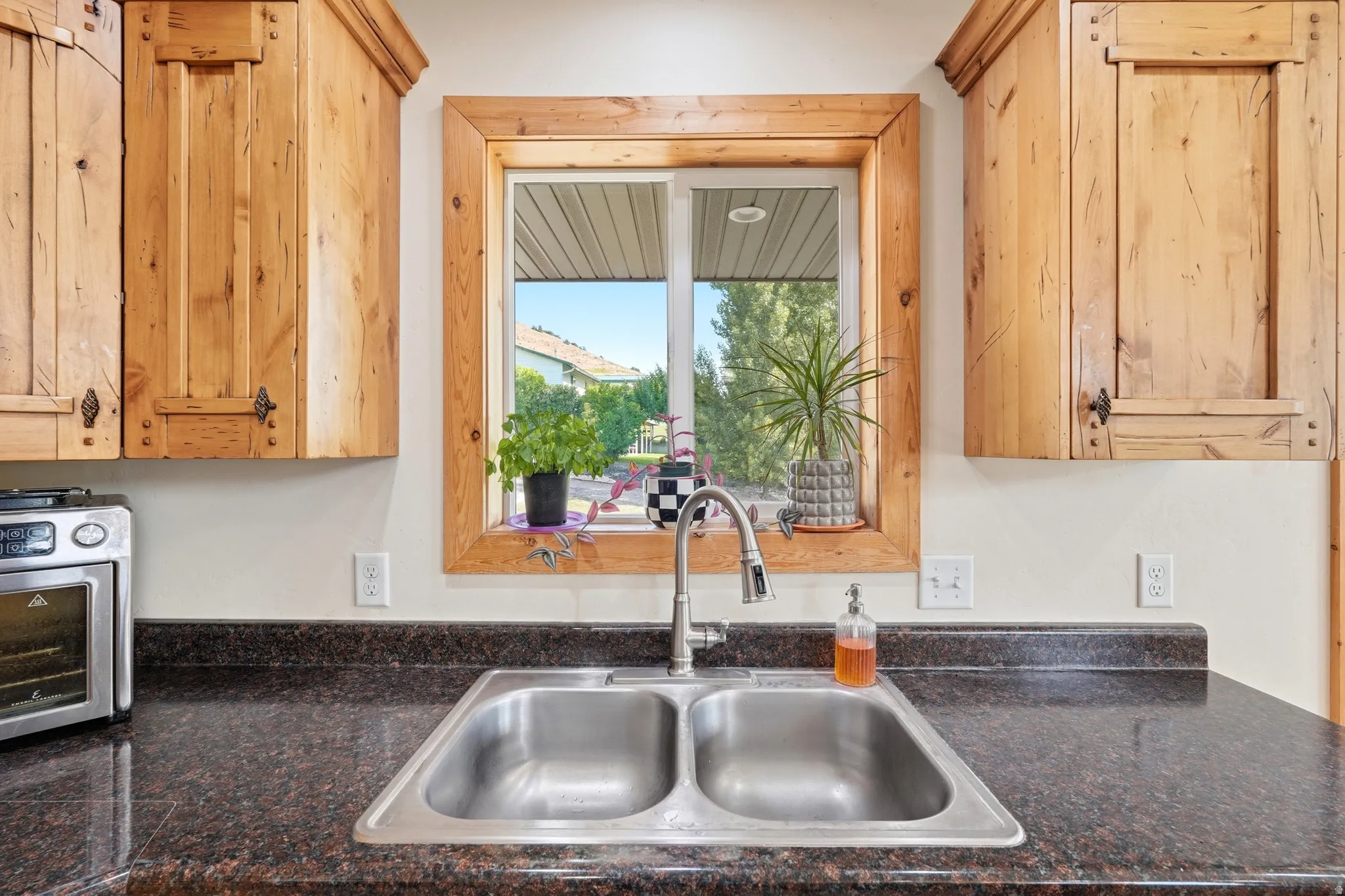 Kitchen workstation featuring a double basin stainless steel sink with a high-arch faucet, set into a dark speckled countertop