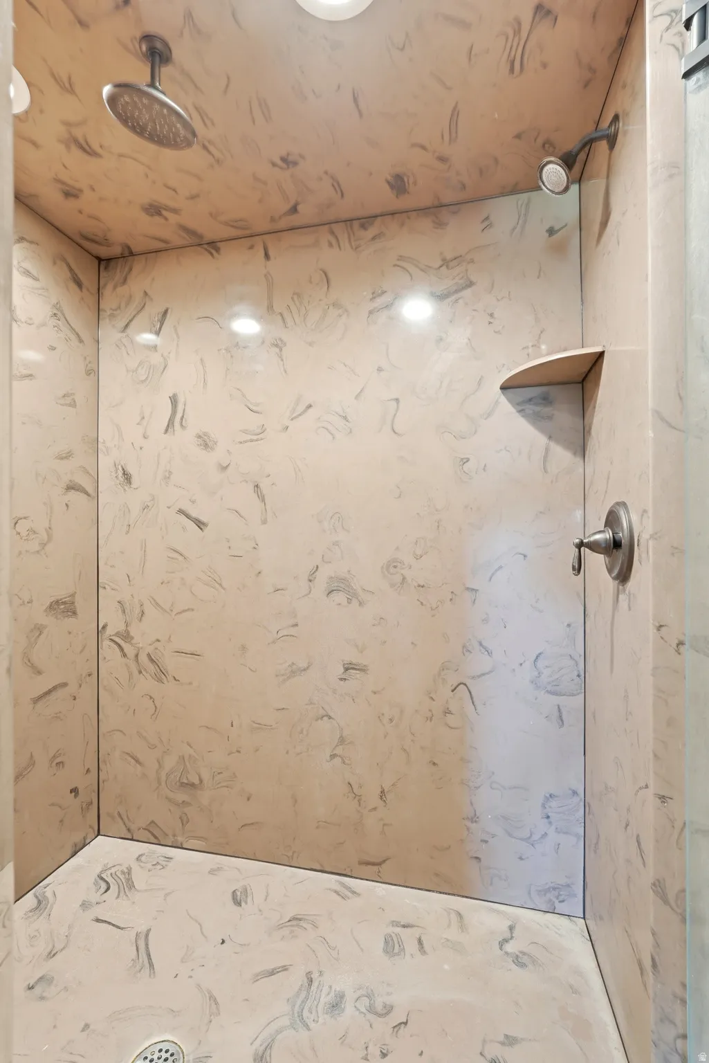 Walk-in shower with swirled wall and floor finishes
