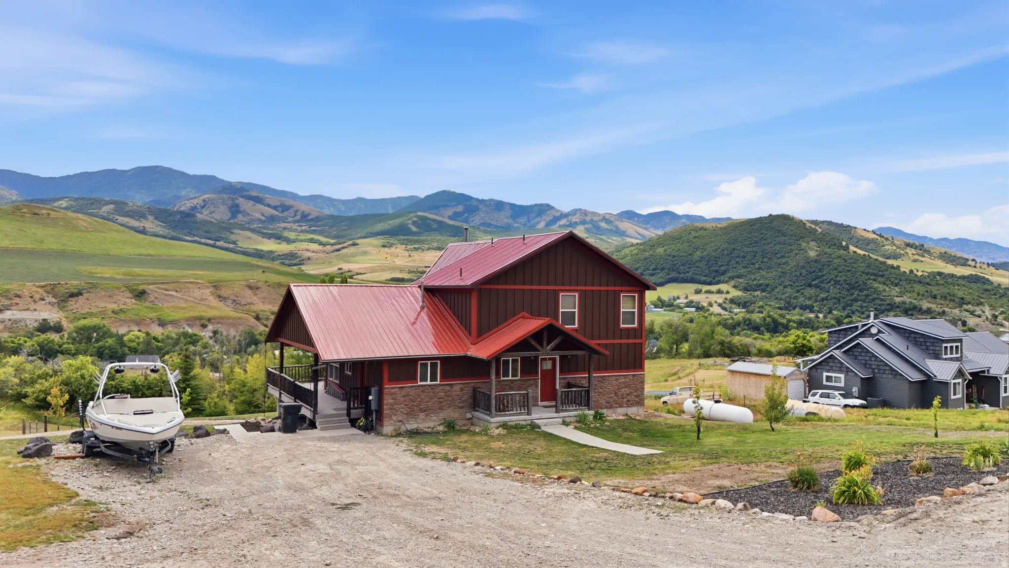 Two-story residence featuring a red metal roof and a stone and wood-paneled exterior