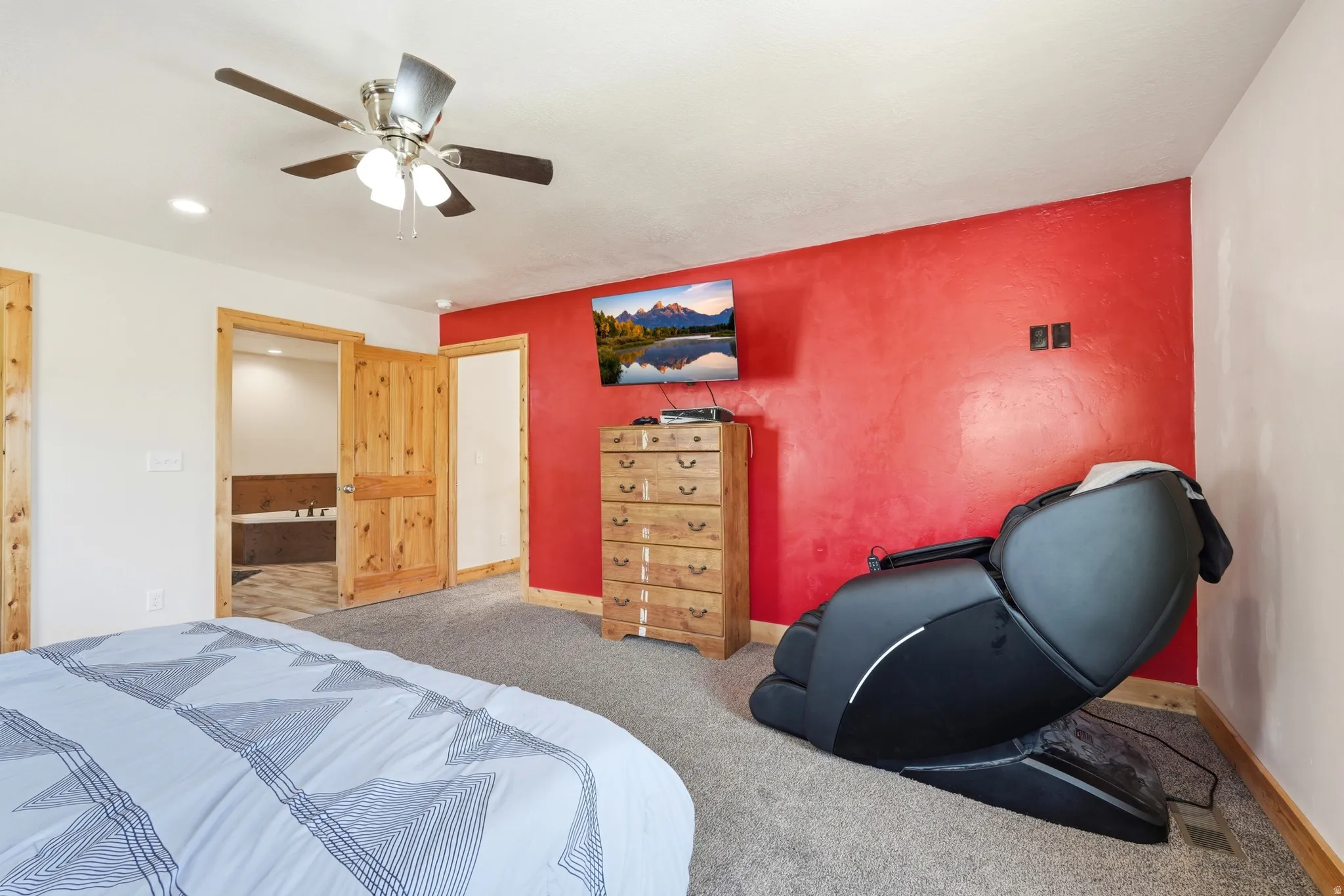 Spacious room featuring a textured red accent wall and light-colored walls