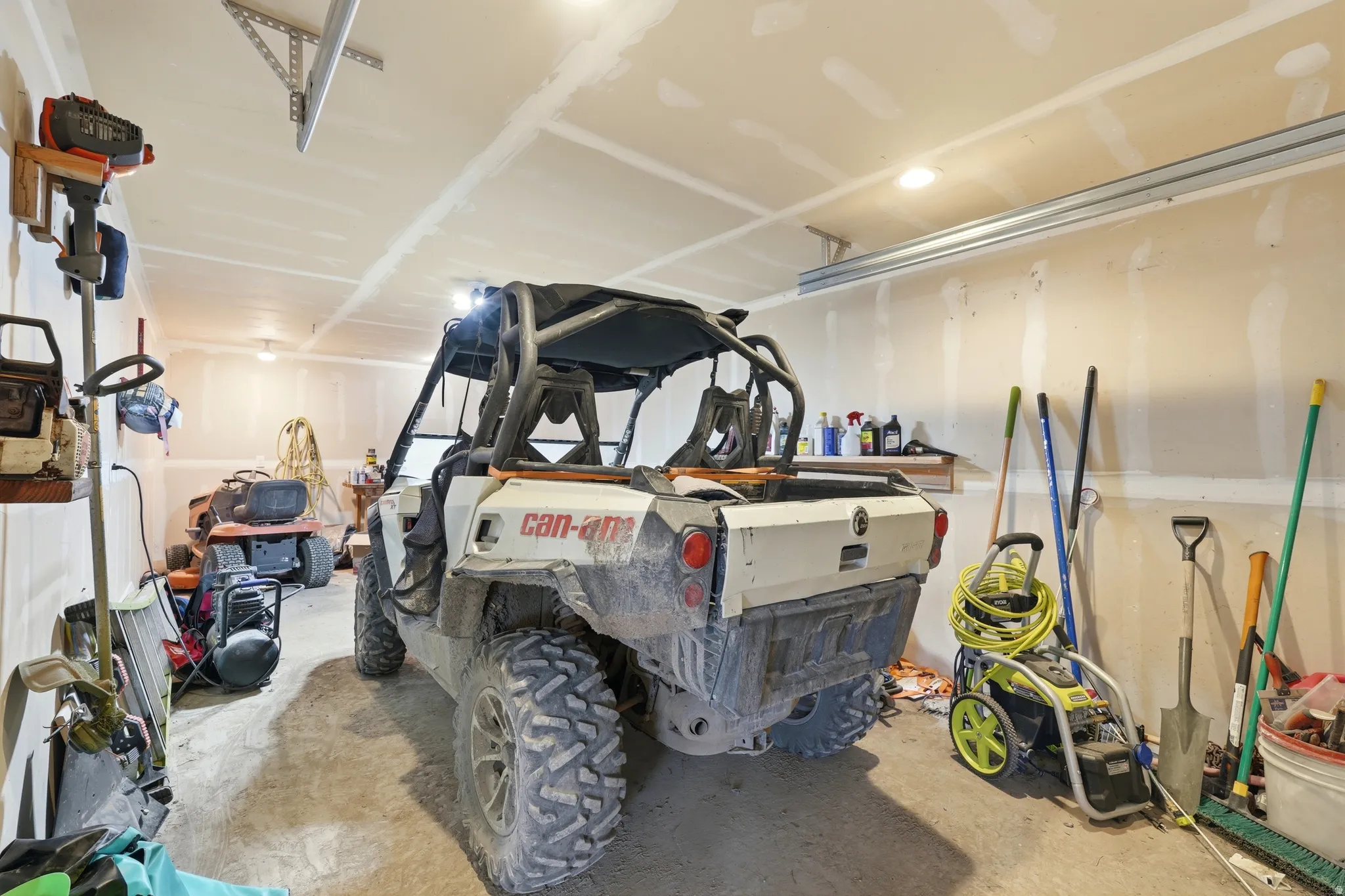 Spacious garage featuring exposed drywall walls and a concrete floor
