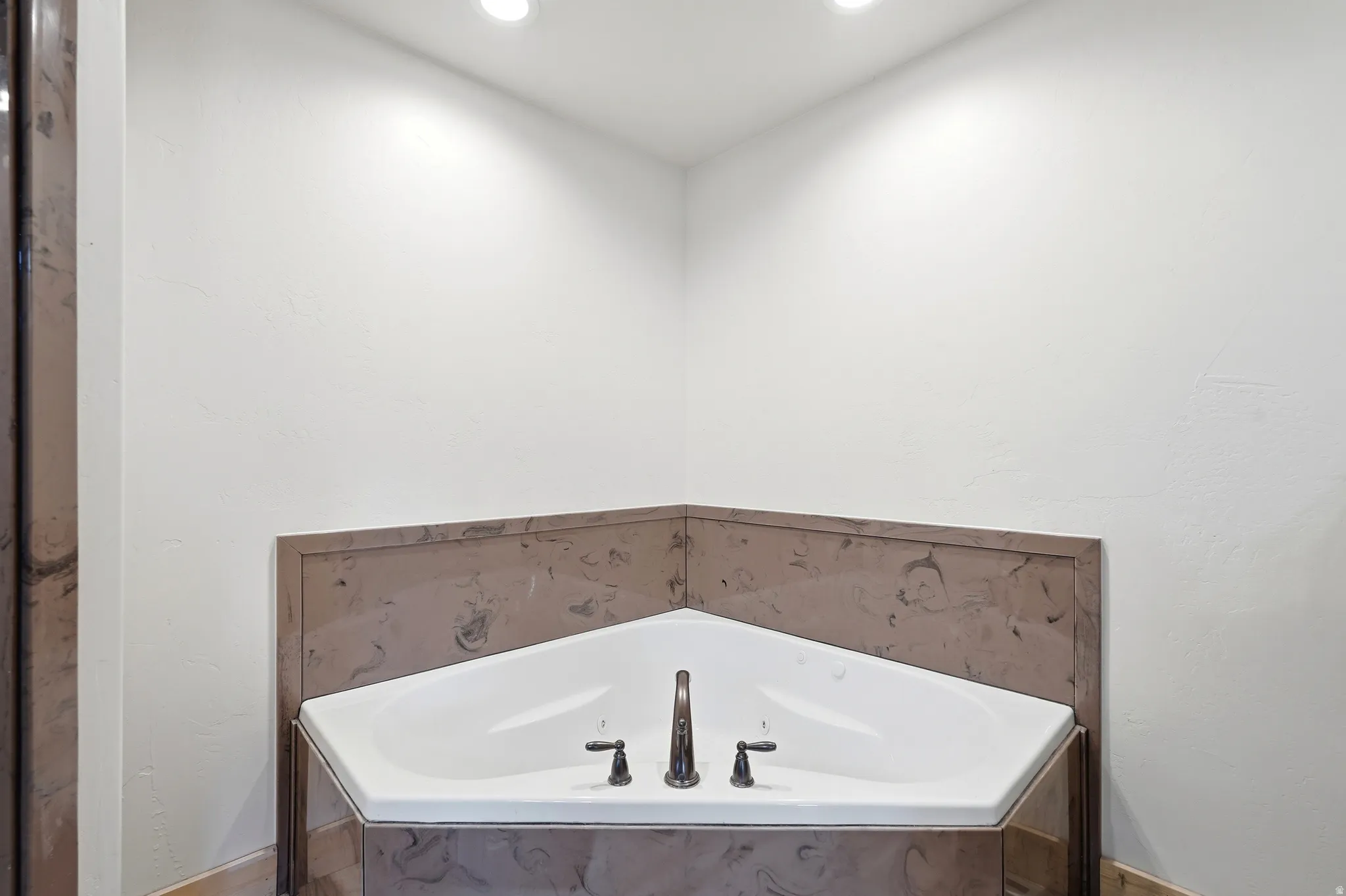 Corner soaking tub with a dark bronze faucet and separate handles