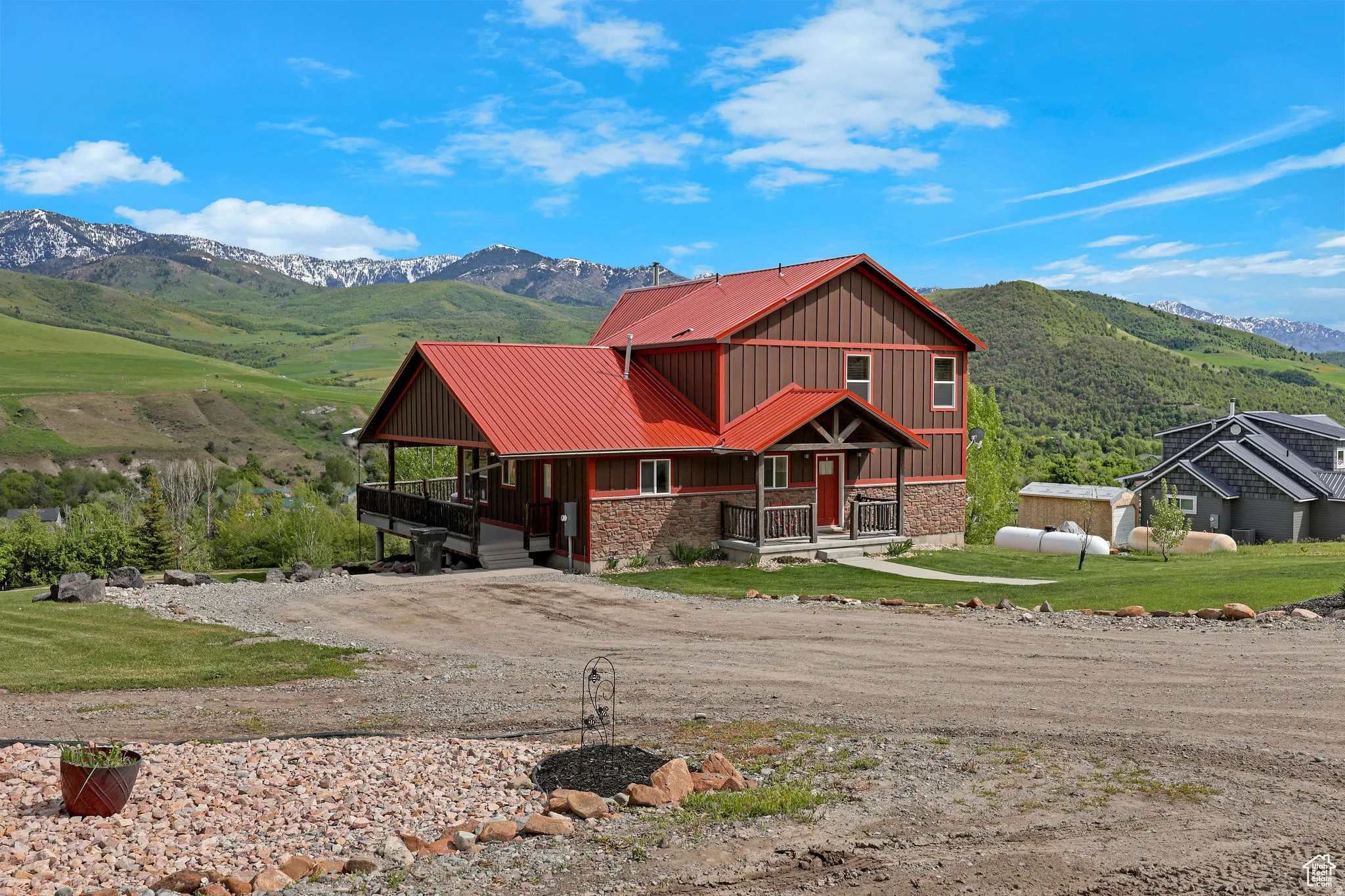 Two-story exterior with a red metal roof, brown siding, and stone accents