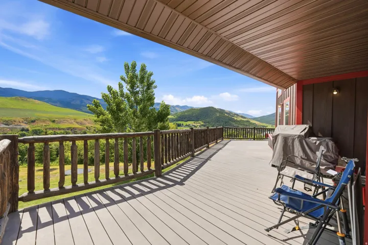 Expansive covered deck featuring composite decking and a rustic wood railing