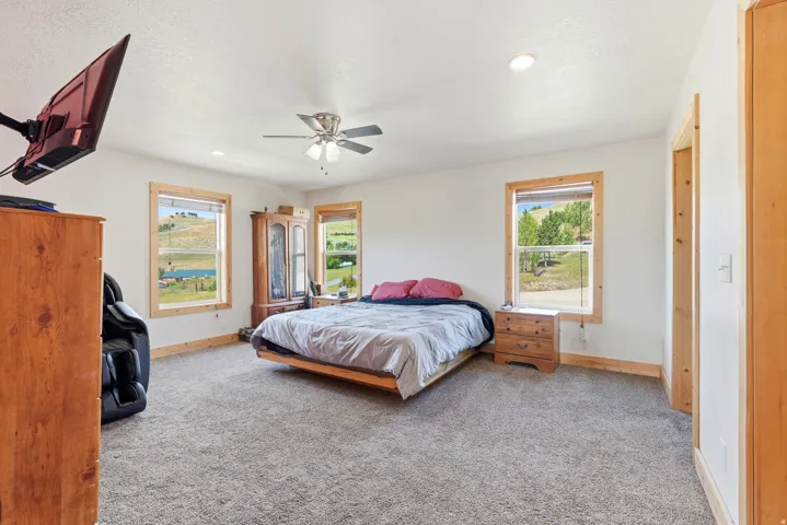 Spacious room featuring light-toned carpeting, white walls, and natural wood trim around windows and doorways