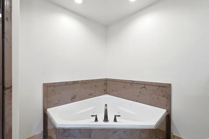 Corner soaking tub with a dark bronze faucet and separate handles