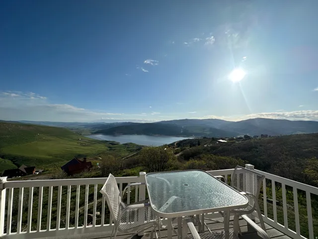 Outdoor deck featuring white railings and expansive lake and mountain scenery
