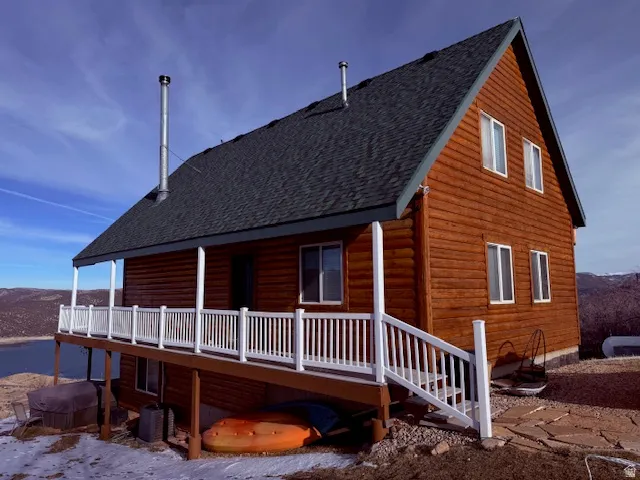Log-sided residence featuring a dark shingled roof and multiple windows