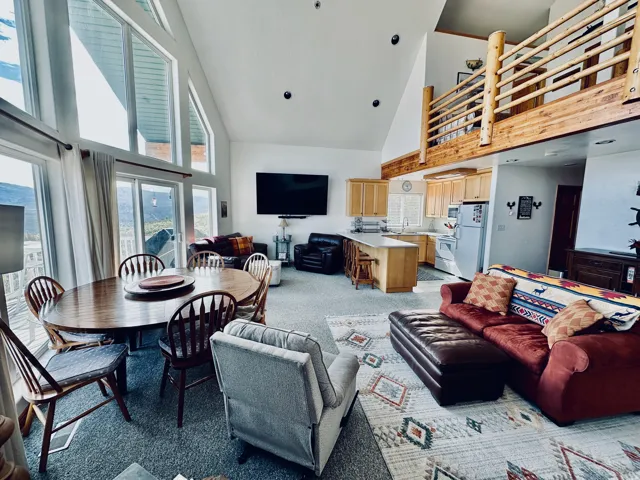 Open-concept living space featuring a vaulted ceiling and a lofted area with a wood railing