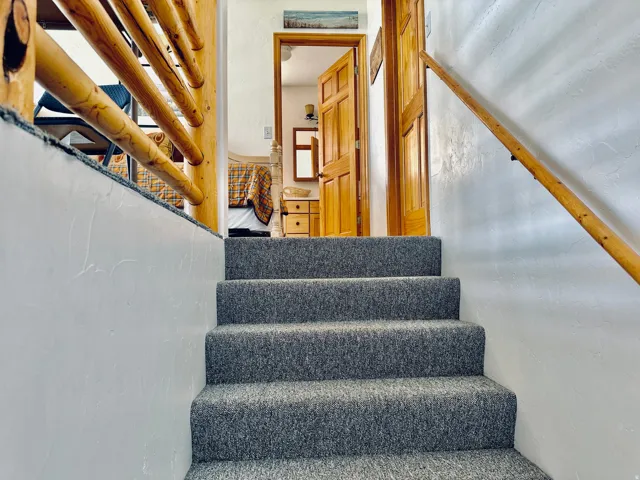 Carpeted staircase with light wood handrails leading to an upper level