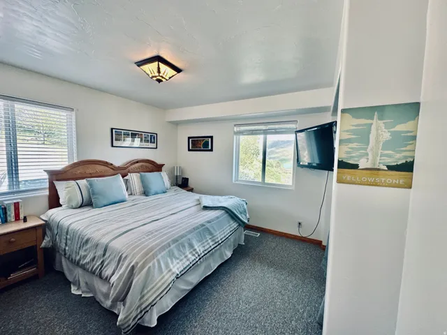 Bedroom featuring a window with horizontal blinds, gray carpet flooring, and a ceiling-mounted light fixture